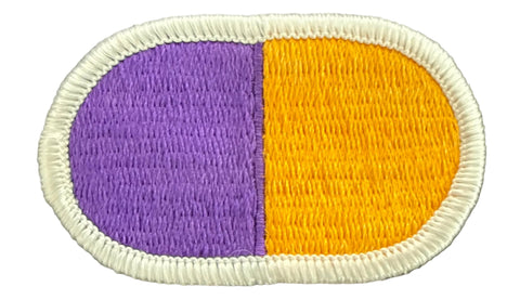 Oval patch with yellow and purple design on a textured surface