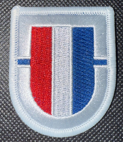 Embroidered patch with red and blue design on a textured background