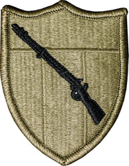 Green shield patch with a black rifle emblem on a white background